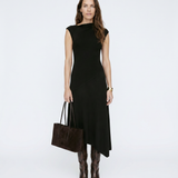 Woman wearing a black dress holding a brown handbag on a white background