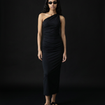 Woman wearing a black one-shoulder dress against a black background