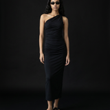 Woman wearing a black one-shoulder dress against a black background