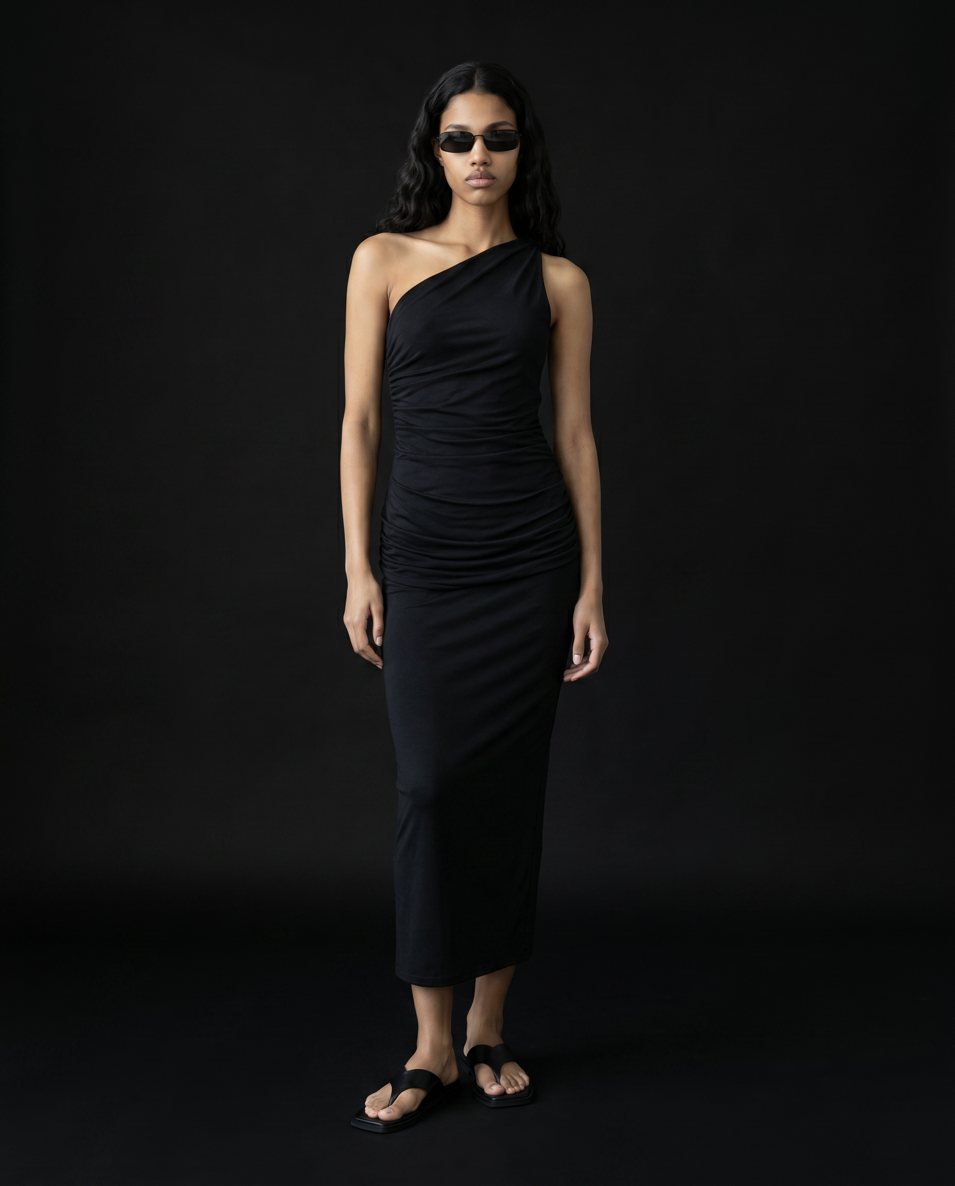 Woman wearing a black one-shoulder dress against a black background