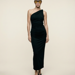 Woman wearing a black one-shoulder dress against a beige background