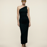 Woman wearing a black one-shoulder dress against a beige background