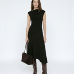 Woman wearing a black dress with brown boots and a handbag on a white background