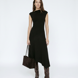 Woman wearing a black dress with brown boots and a handbag on a white background