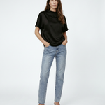 Woman wearing a black top and light blue jeans on a white background