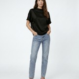 Woman wearing a black top and light blue jeans on a white background