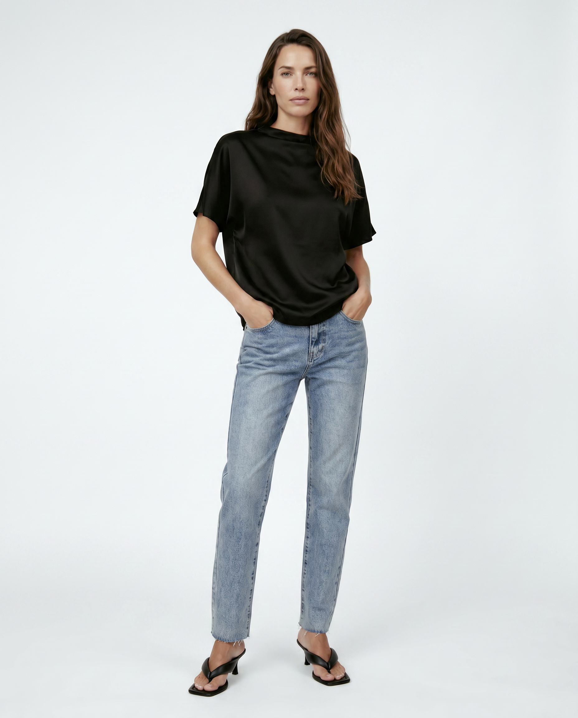 Woman wearing a black top and light blue jeans on a white background