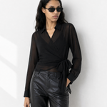 Woman wearing a black blouse and leather shorts with sunglasses on a white background