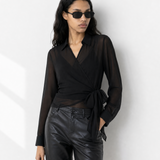 Woman wearing a black blouse and leather shorts with sunglasses on a white background