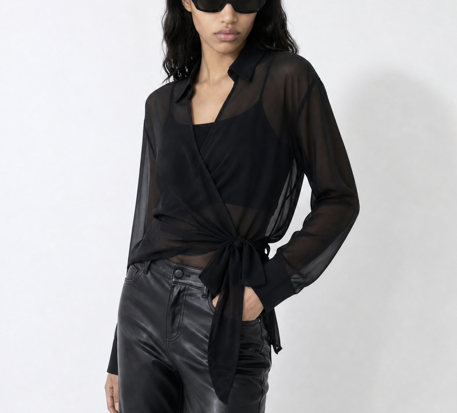 Woman wearing a black outfit with sheer overlay on a white background
