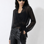 Woman wearing a black outfit with sheer overlay on a white background