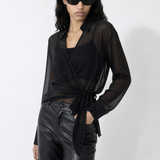 Woman wearing a black outfit with sheer overlay on a white background