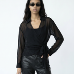 Woman wearing a black sheer top and leather pants with sunglasses on a white background