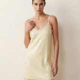 Woman wearing an ivory lace sequin dress against a plain background