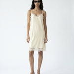 Woman wearing a cream slip dress on a white background