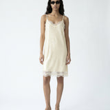 Woman wearing a cream slip dress on a white background