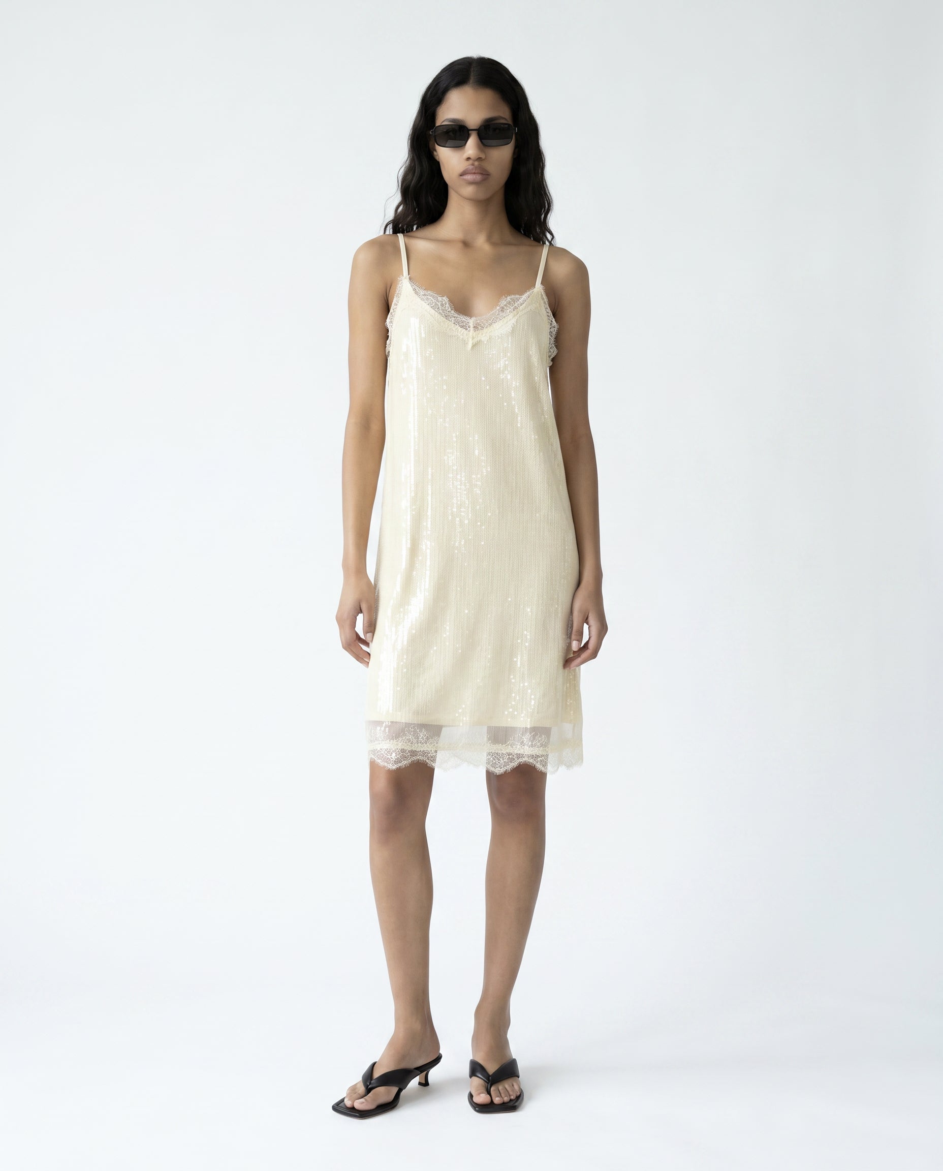 Woman wearing a cream slip dress on a white background