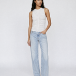 A model stands against a light gray studio background wearing a white sleeveless ruched top, light-wash wide-leg jeans, and leopard-print sandals.