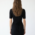 Woman wearing a black ribbed dress against a white background