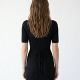 Woman wearing a black ribbed dress against a white background