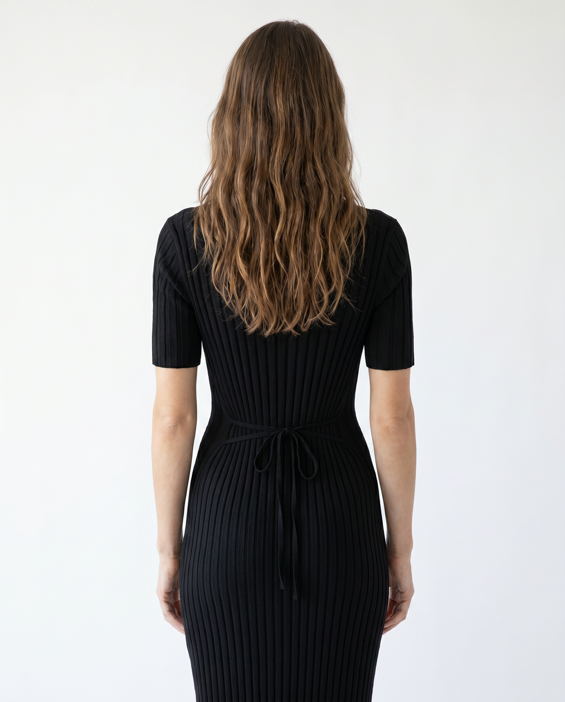 Woman wearing a black ribbed dress against a white background