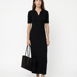 Woman wearing a black dress holding a black bag on a white background