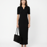 Woman wearing a black dress holding a black bag on a white background