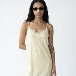 Woman wearing a light-colored slip dress on a white background