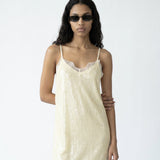 Woman wearing a light-colored slip dress on a white background