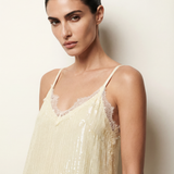 Woman wearing a beige lace-trimmed top against a plain background