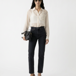 Woman wearing a beige blouse and black pants with sunglasses on a white background