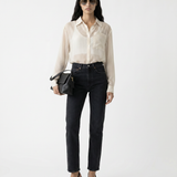 Woman wearing a beige blouse and black pants with sunglasses on a white background