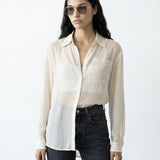 Woman wearing a light-colored striped shirt and dark jeans on a white background