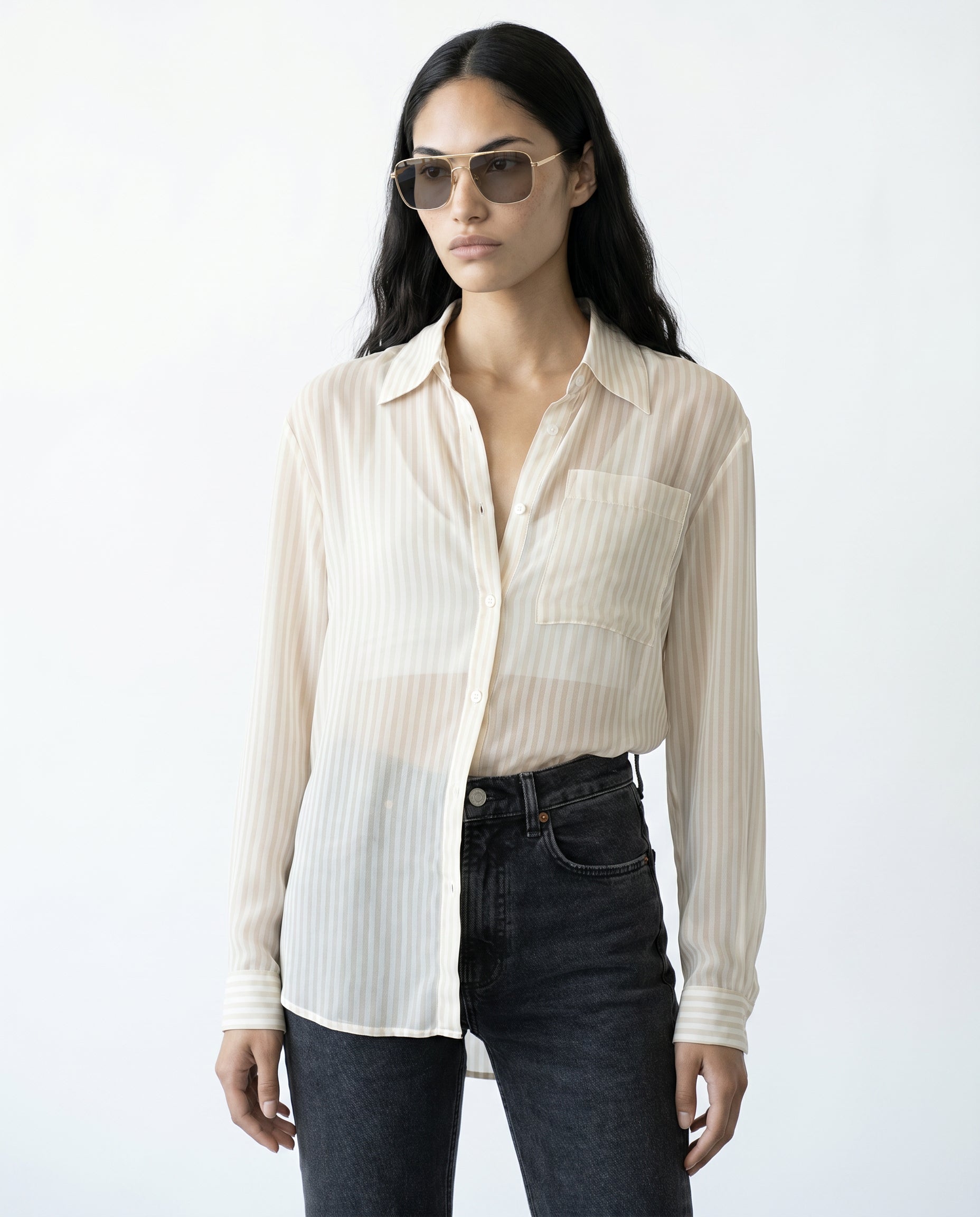 Woman wearing a light-colored striped shirt and dark jeans on a white background