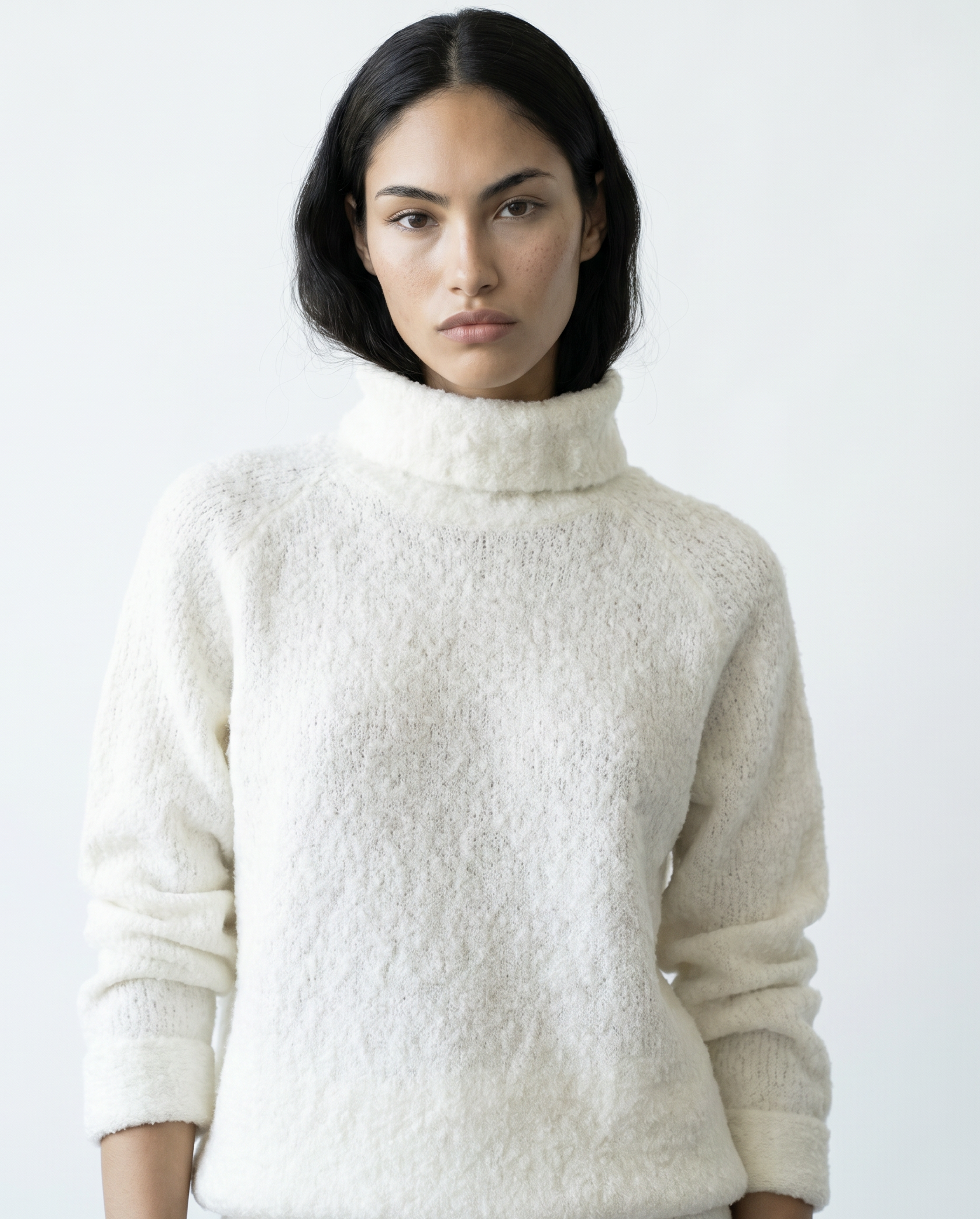 Woman wearing a textured white sweater against a plain background