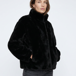 Woman wearing a black faux fur jacket on a white background