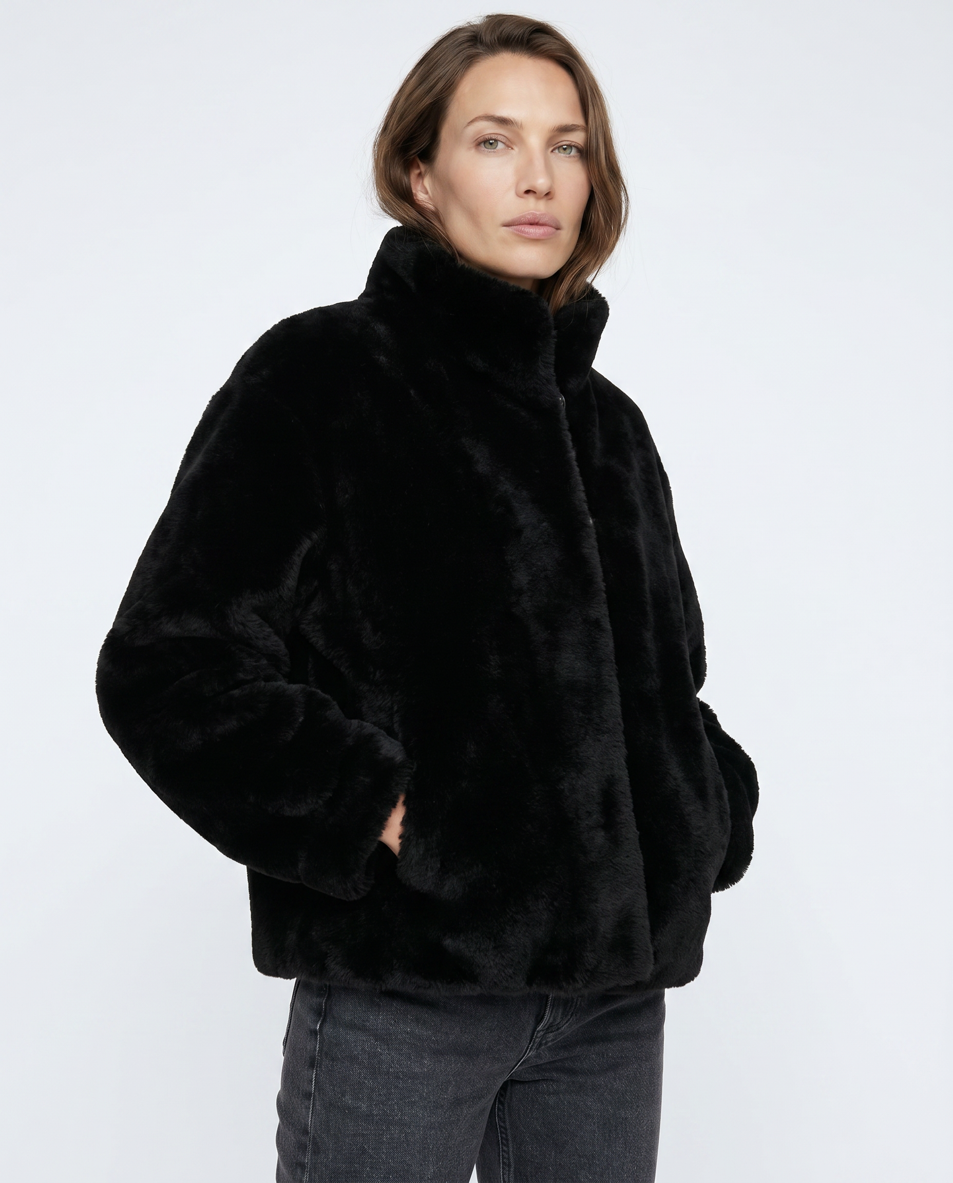 Woman wearing a black faux fur jacket on a white background